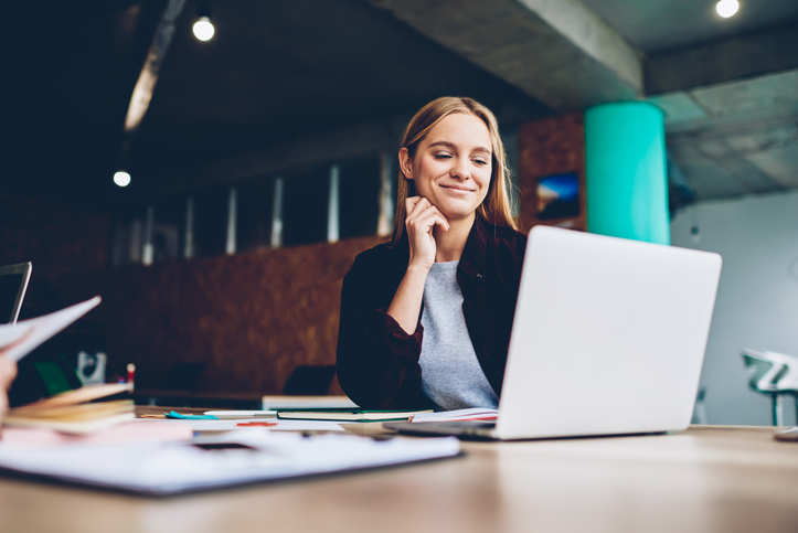 Jovem mulher sentada à mesa utilizando um notebook, concentrada em seus estudos e representando a preparação feminina para o mercado de tecnologia.