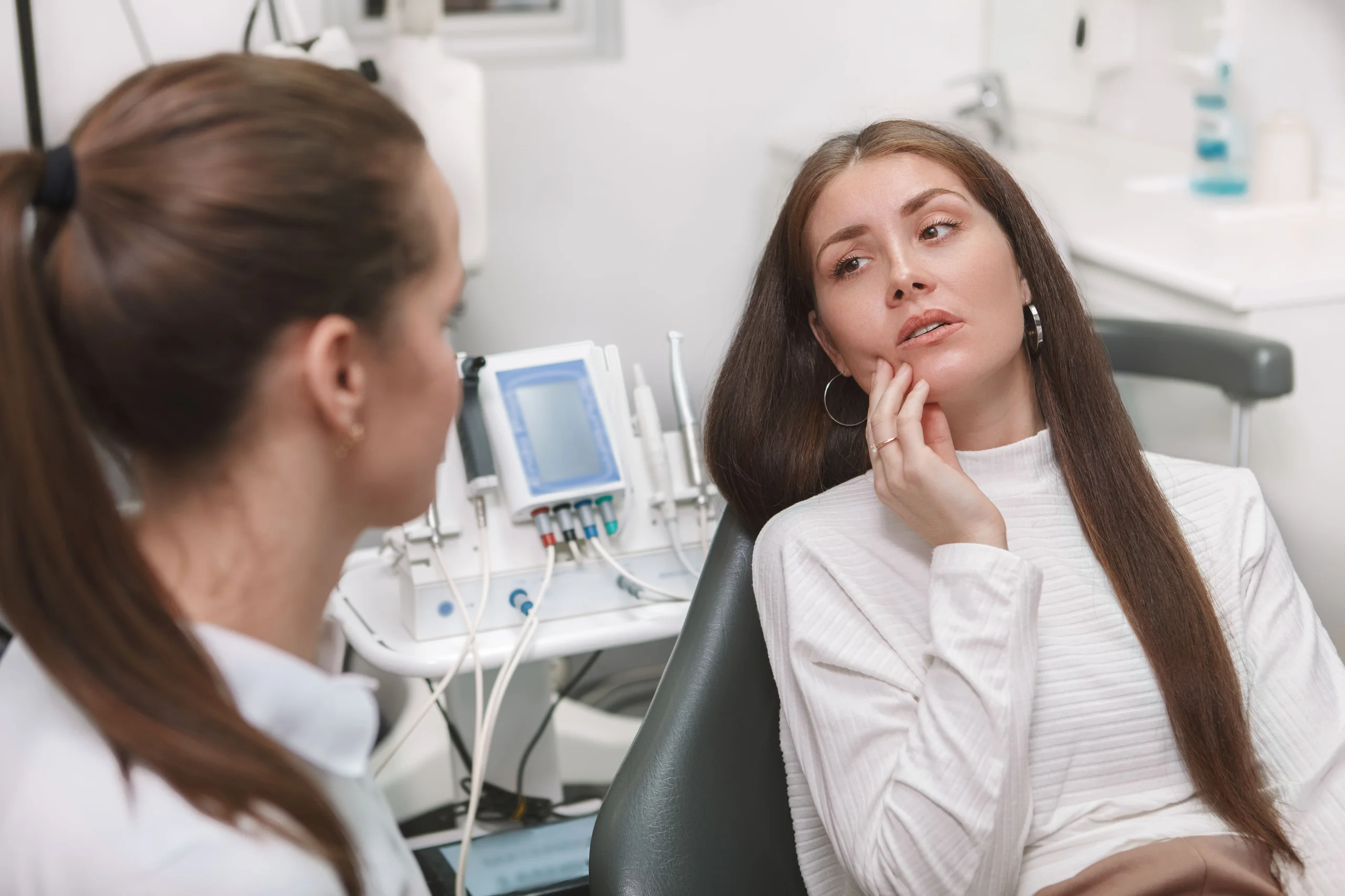 Paciente conversando com dentista sobre sintomas de dor durante consulta odontológica profissional