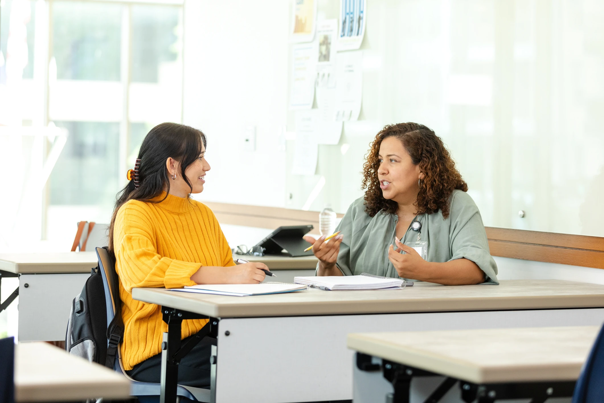 Estudante e professora conversando em uma sala de aula