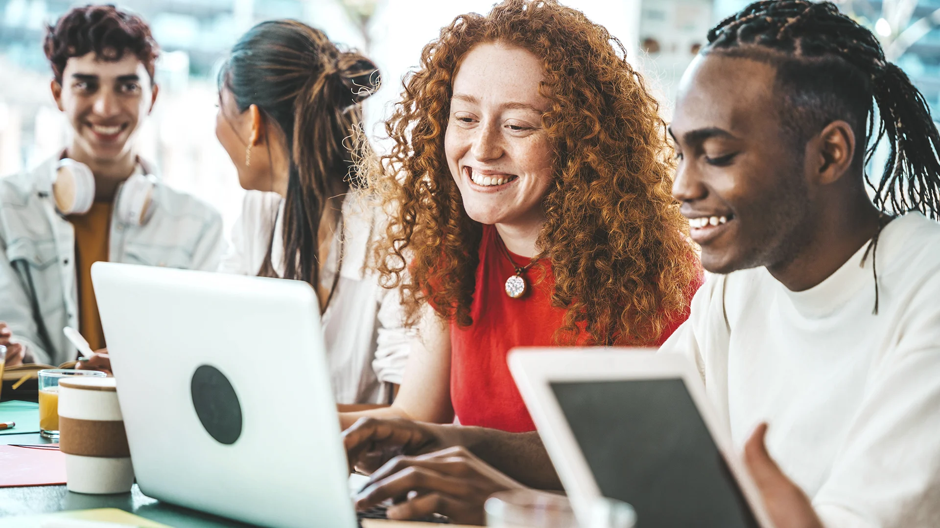 Grupo de estudantes diversos trabalhando juntos em um projeto universitário com laptop e tablet