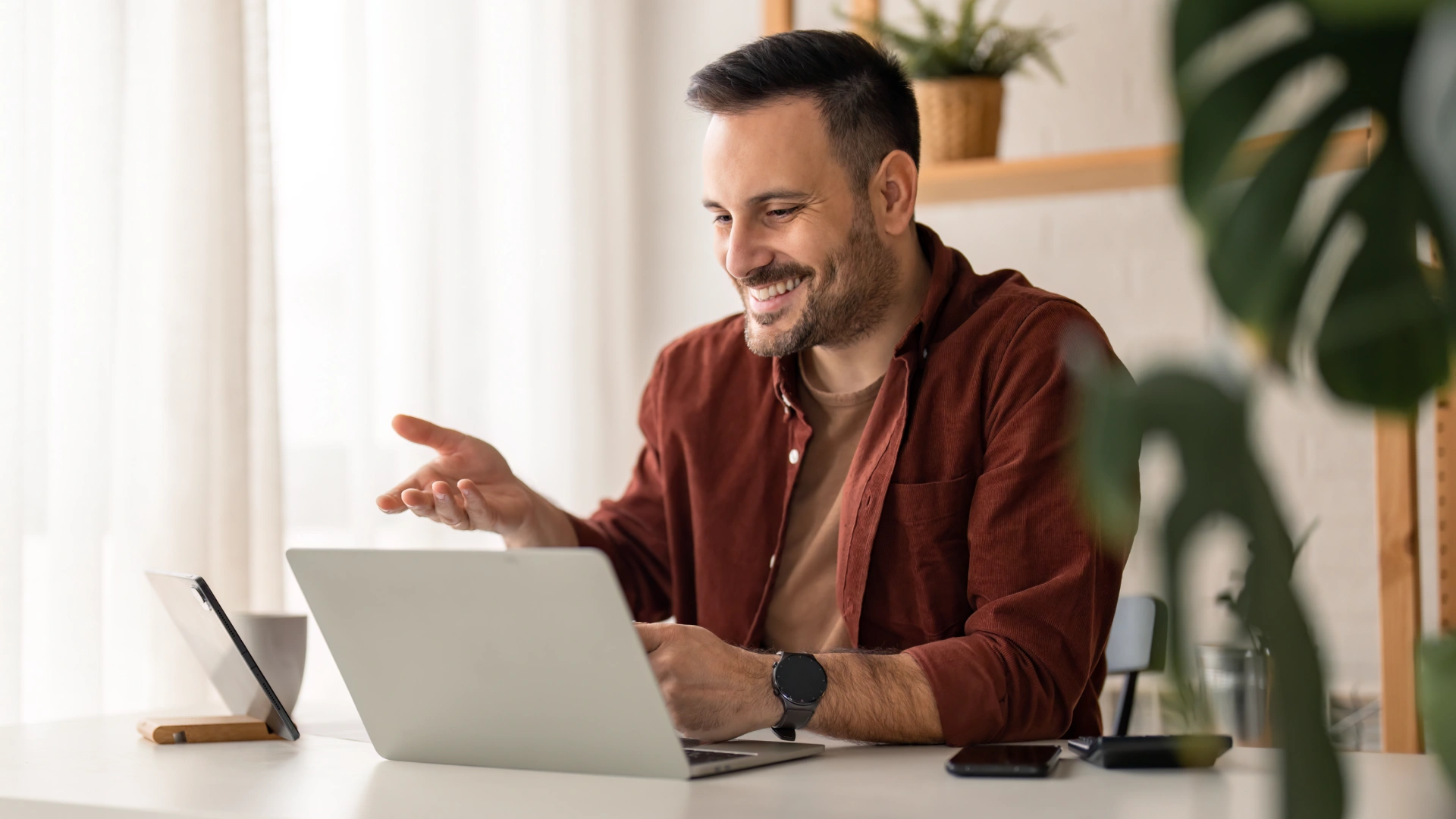 Homem feliz trabalhando remotamente em seu home office com notebook, ideal para representar produtividade e trabalho flexível