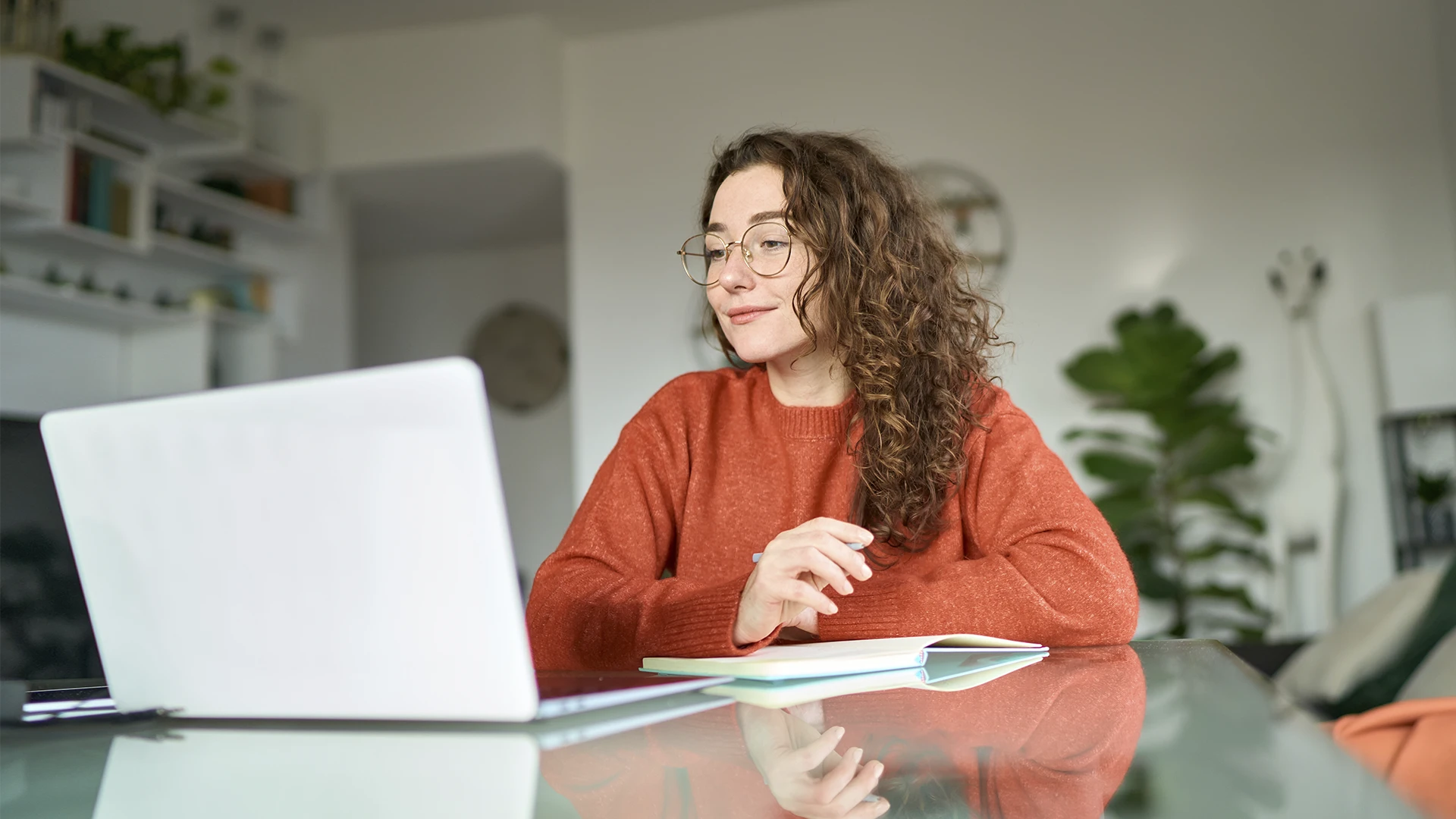 Estudante focada em home office usando notebook e fazendo anotações
