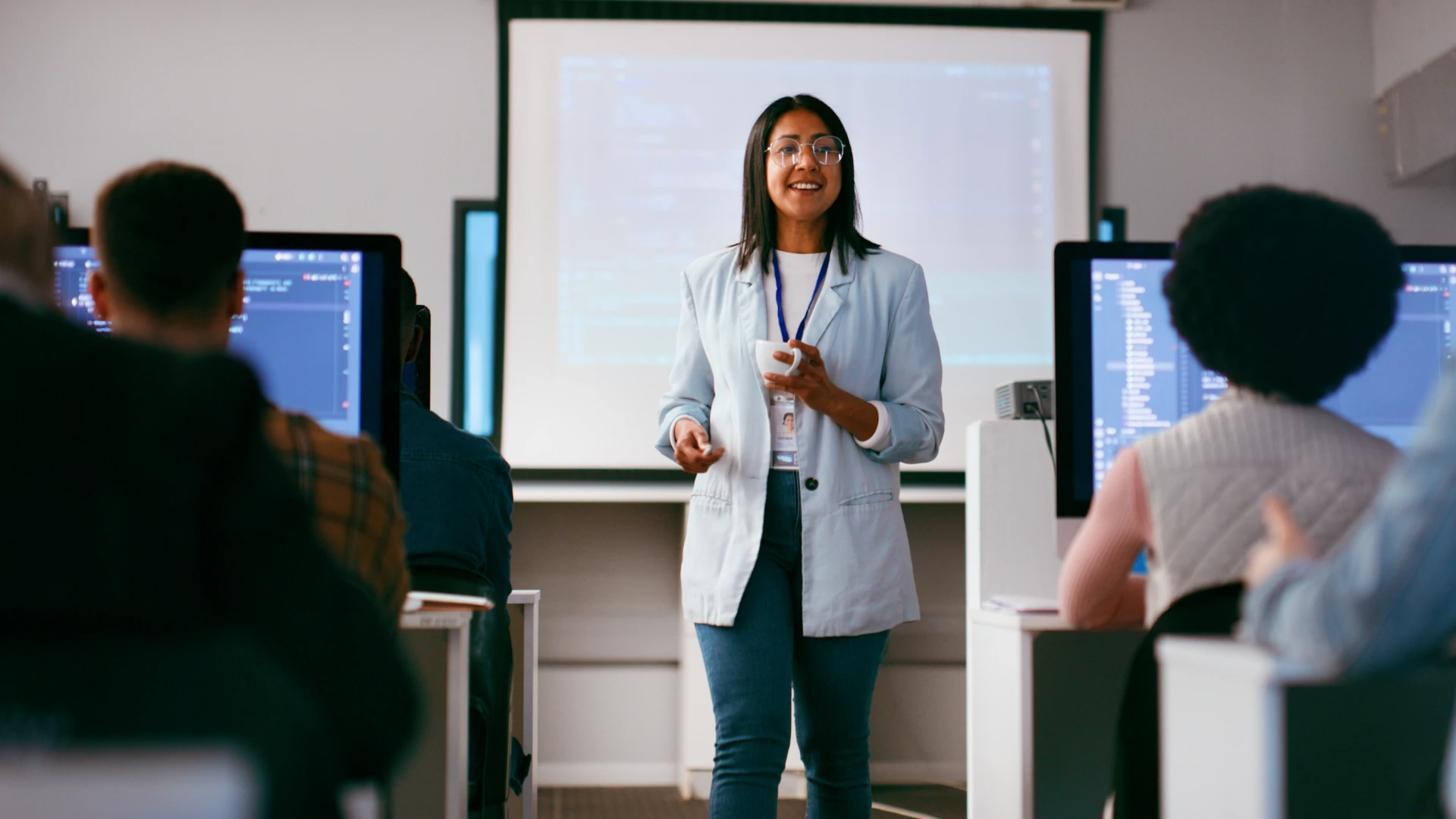Professora universitária liderando aula prática de desenvolvimento de software para estudantes em laboratório
