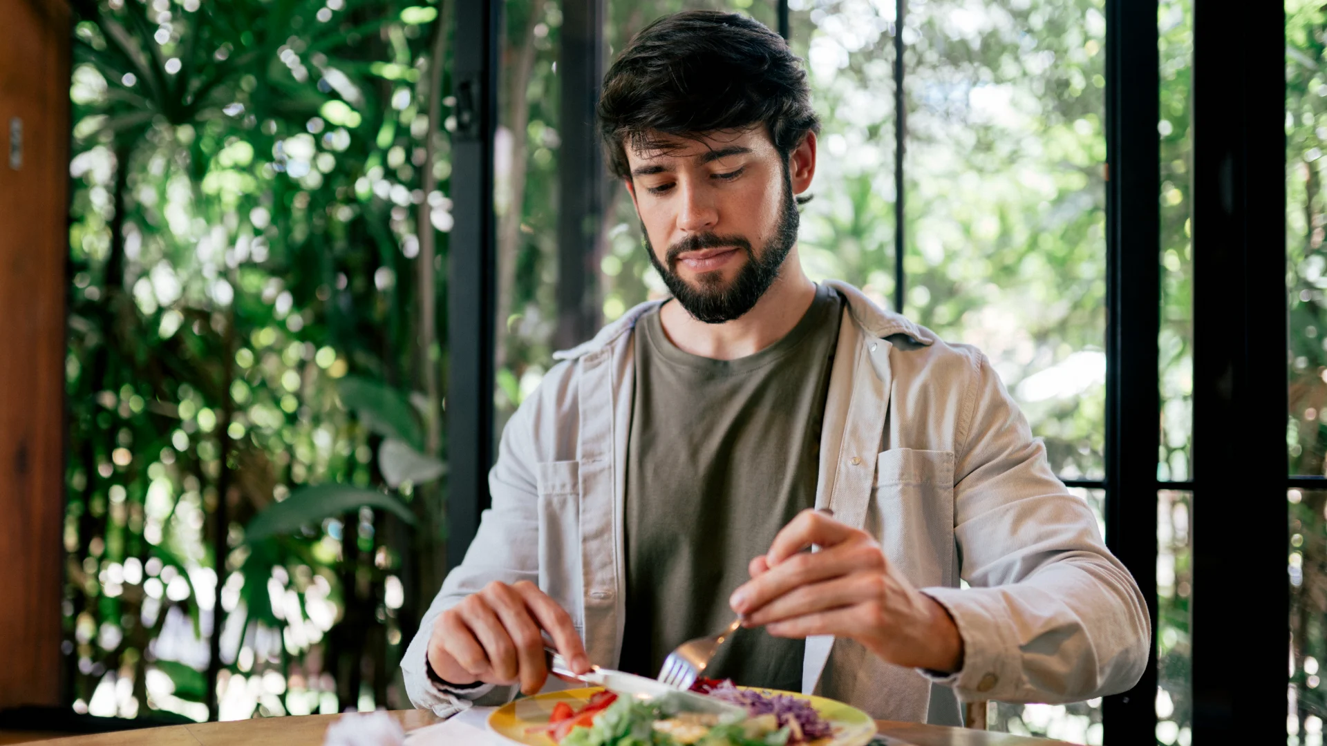 Homem jovem e barbudo desfrutando de uma refeição saudável e nutritiva em um ambiente natural e iluminado