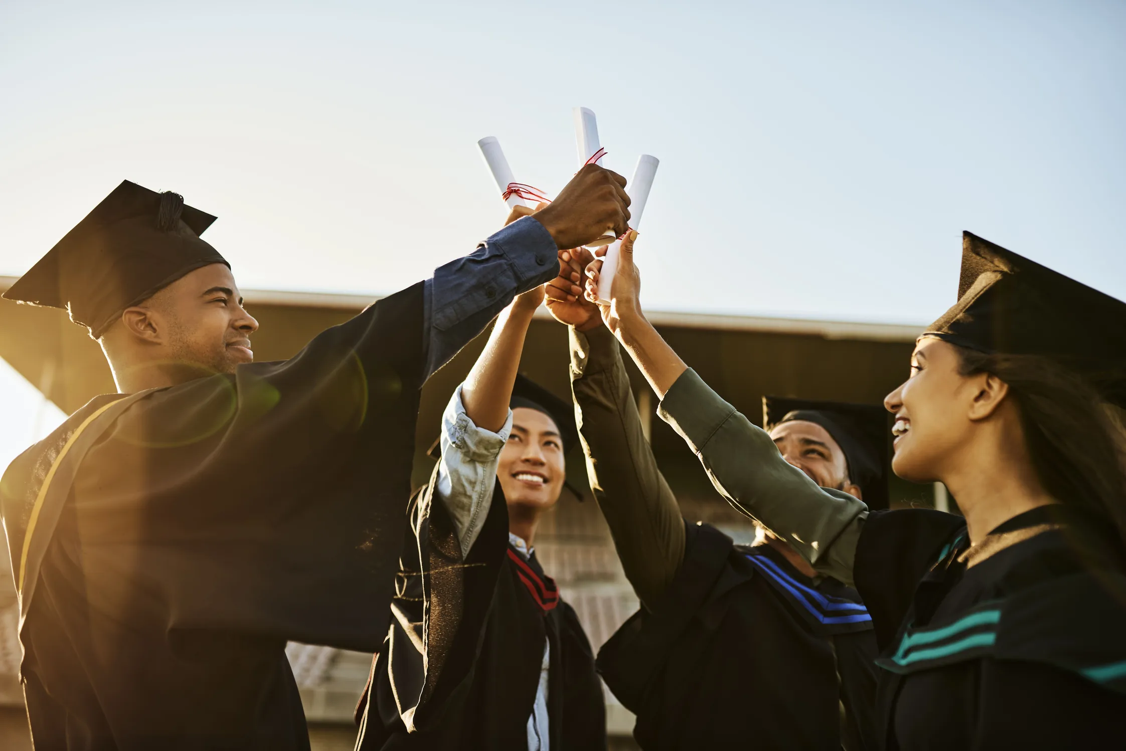 Estudantes universitários comemorando a formatura e o sucesso acadêmico com diplomas em mãos