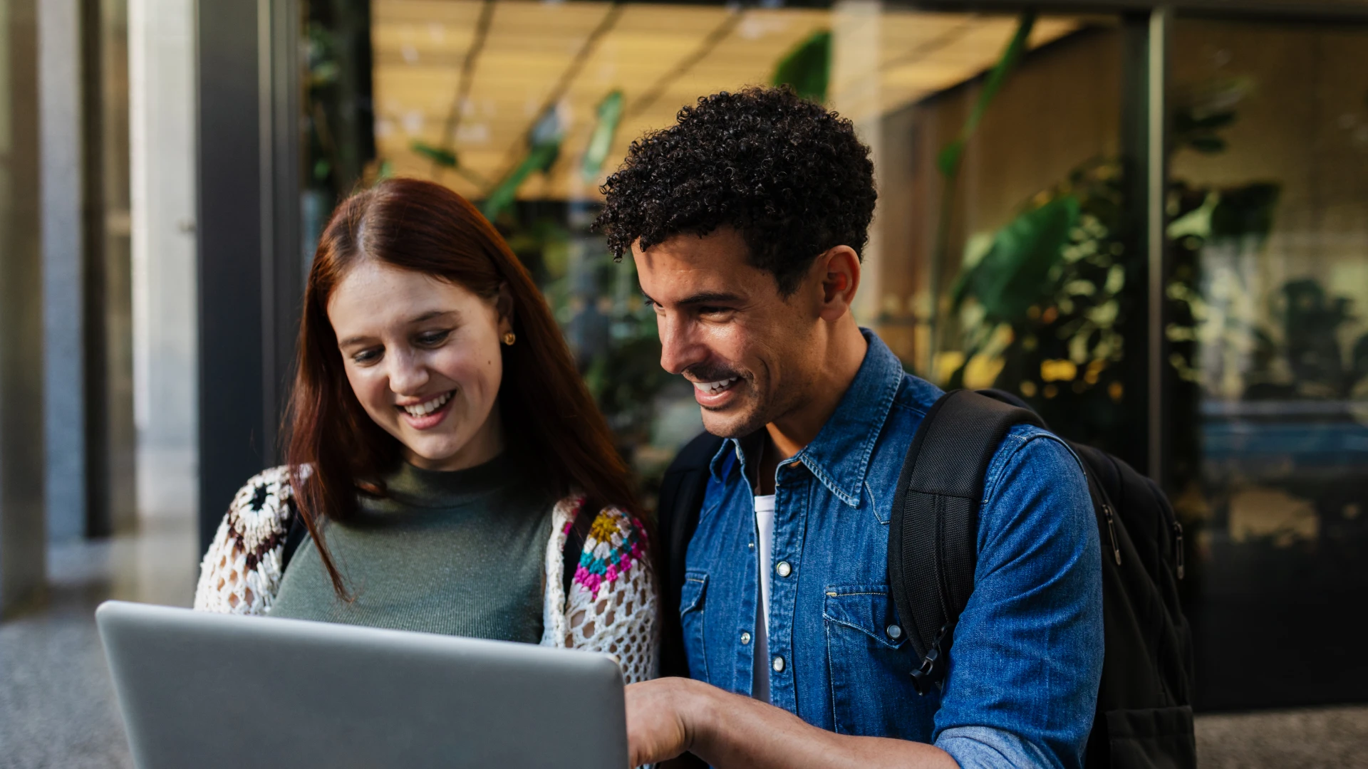 Estudantes universitários sorridentes usando um notebook em um campus moderno