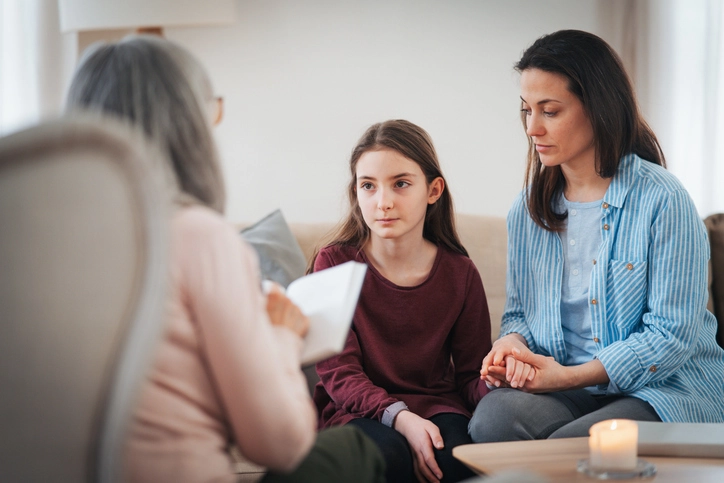 Descubra como é a rotina de um psicólogo e entenda o funcionamento do curso de faculdade de psicologia Psicóloga realizando atendimento clínico com uma criança e sua mãe em consultório