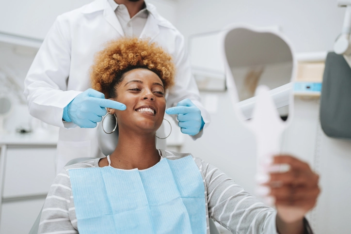 Conheça o curso de Odontologia e a excelência no atendimento clínico para a saúde bucal dos pacientes Dentista examinando o sorriso de uma paciente em consulta odontológica