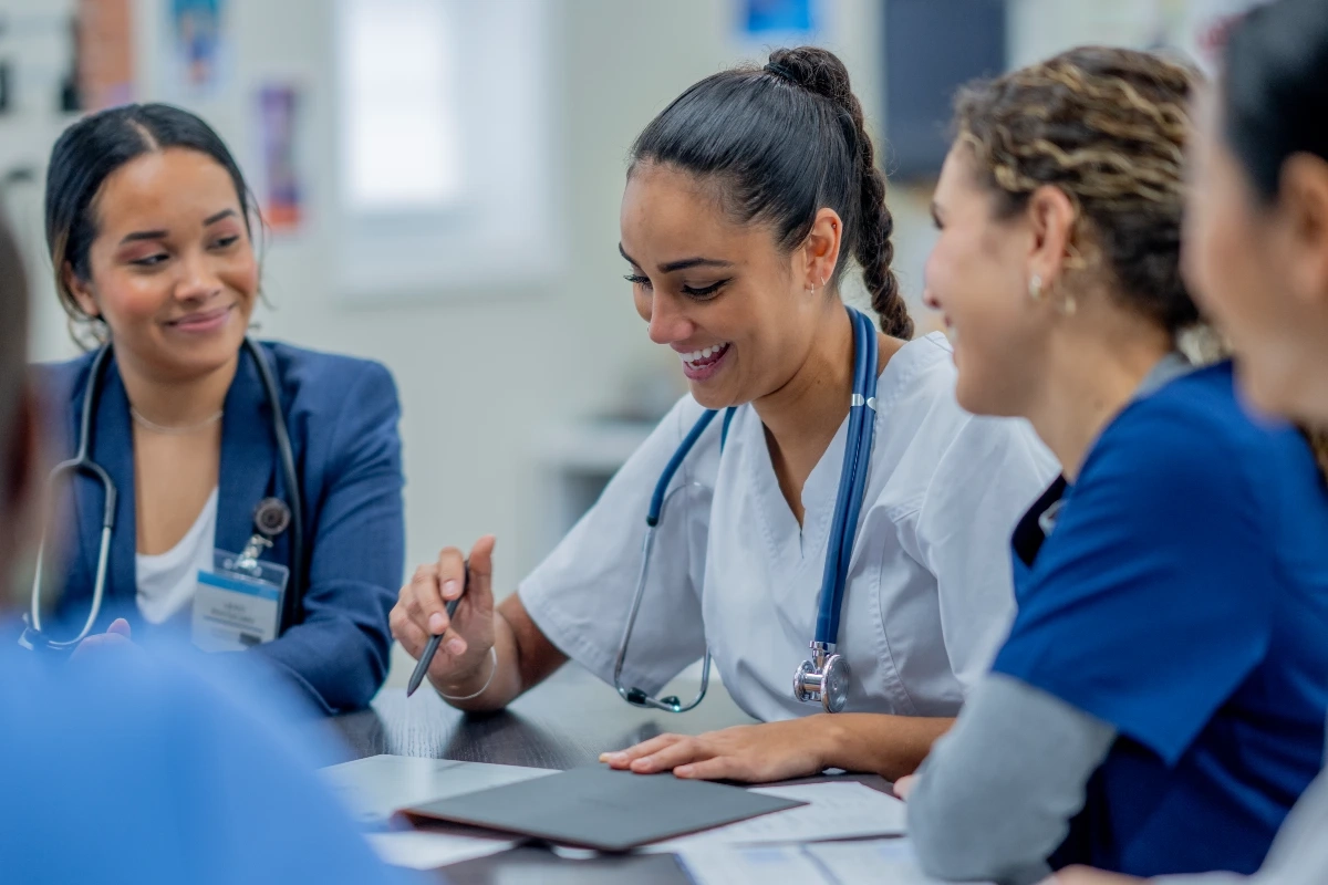 Grupo de estudantes de medicina sorridentes reunidos em mesa de estudos durante aula prática