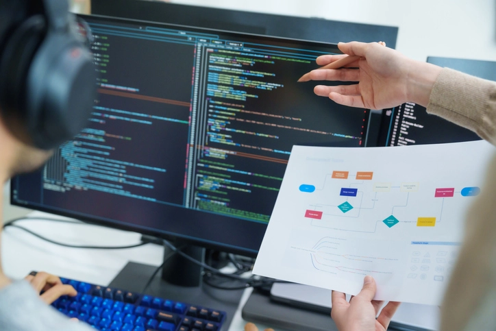 Estudante de Análise e Desenvolvimento de Sistemas programando em computador com auxílio de fluxograma
