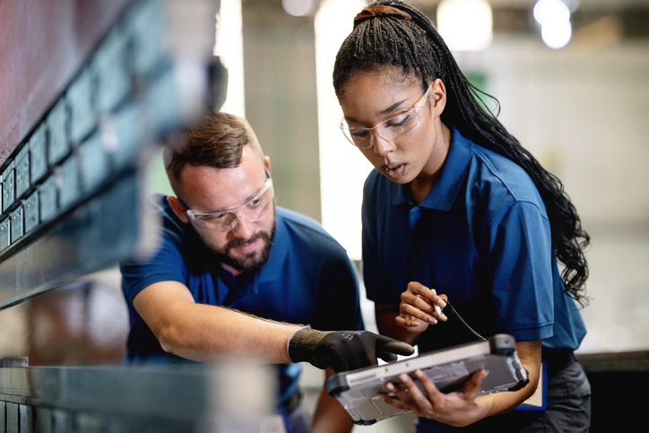 Estudantes de engenharia e tecnologia utilizando tablet em ambiente de fábrica