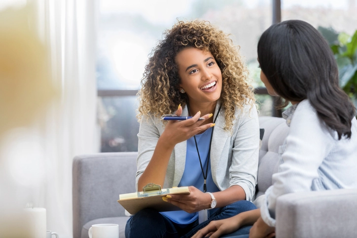 Psicóloga sorrindo durante sessão de terapia e conversa com paciente em consultório