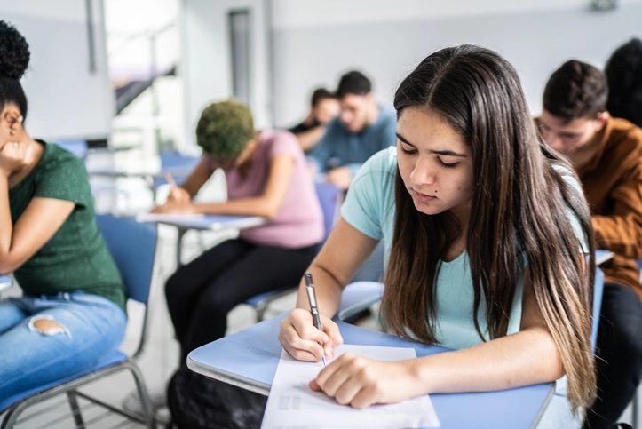 Estudantes concentrados realizando uma prova em sala de aula durante o vestibular