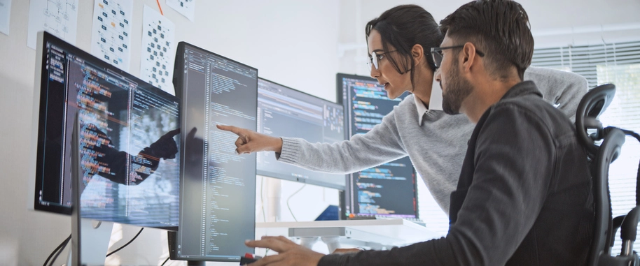 Estudantes de Engenharia de Computação colaborando em projeto de programação em frente a monitores