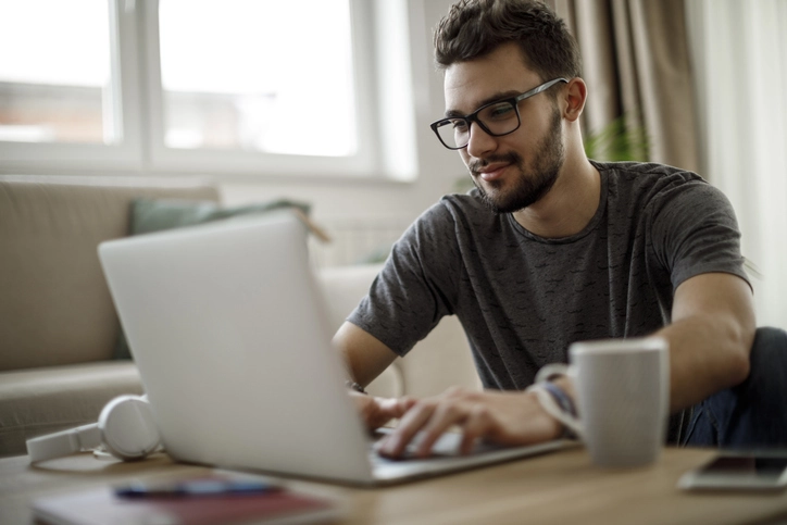 Jovem estudante utilizando notebook em casa para pesquisar cursos universitários