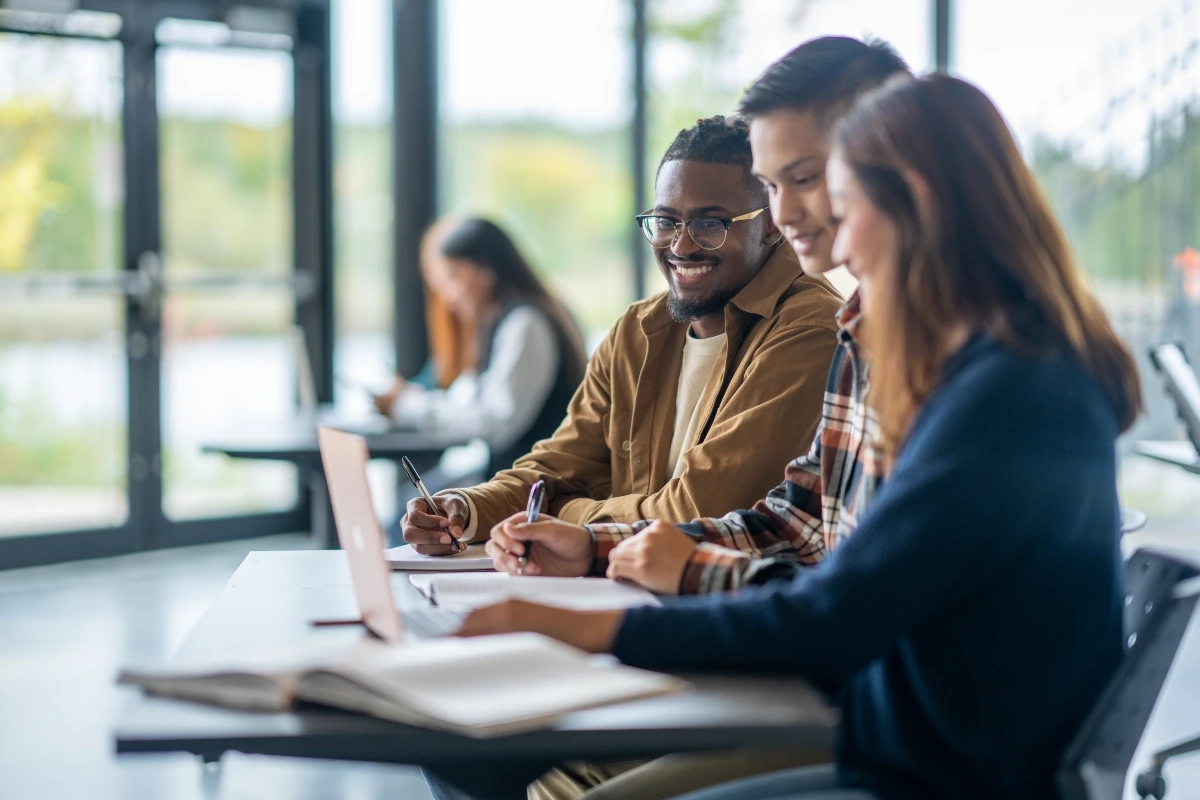 Grupo de estudantes universitários diversos estudando juntos em uma biblioteca moderna
