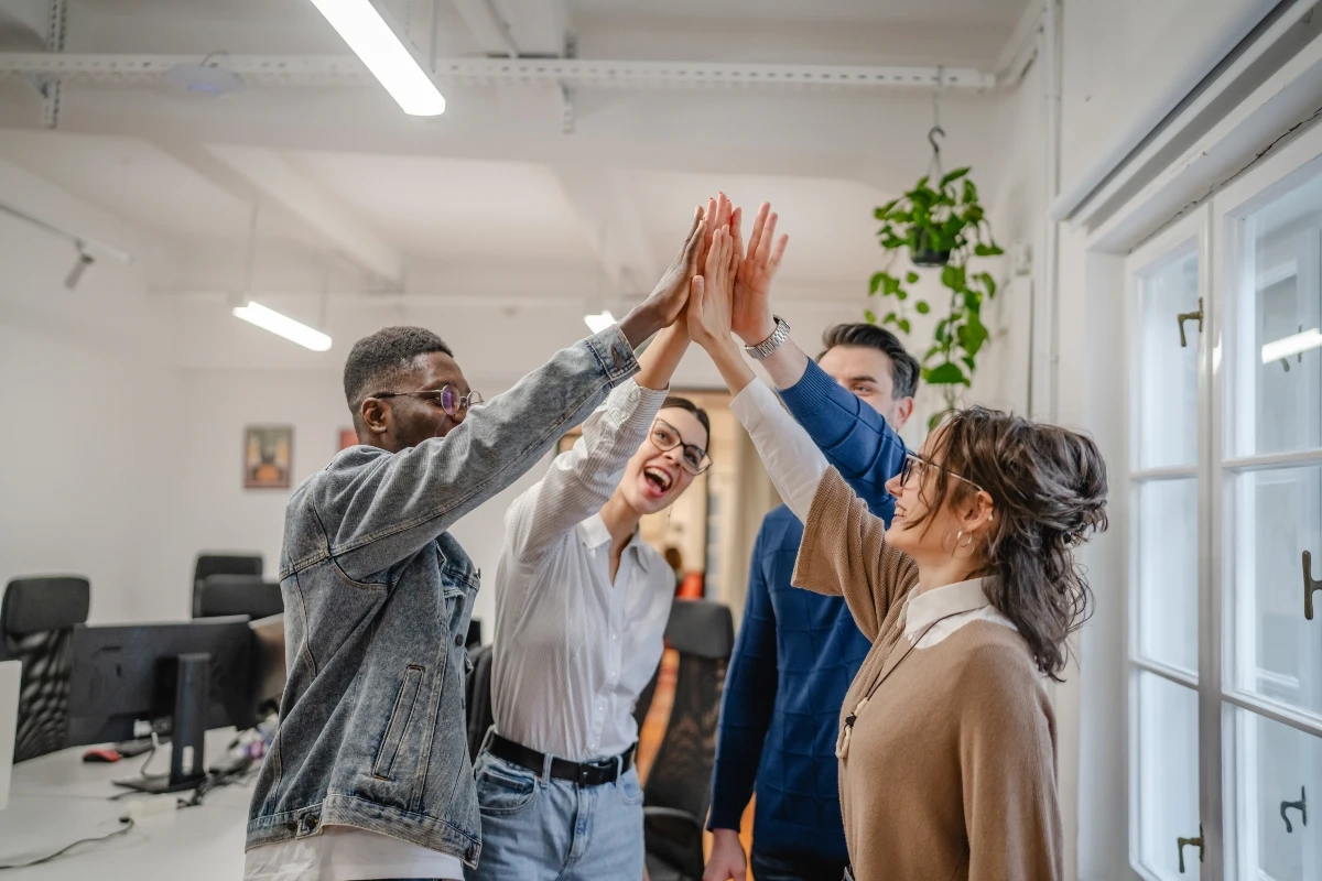 Equipe diversa celebrando sucesso profissional com um high five no escritório