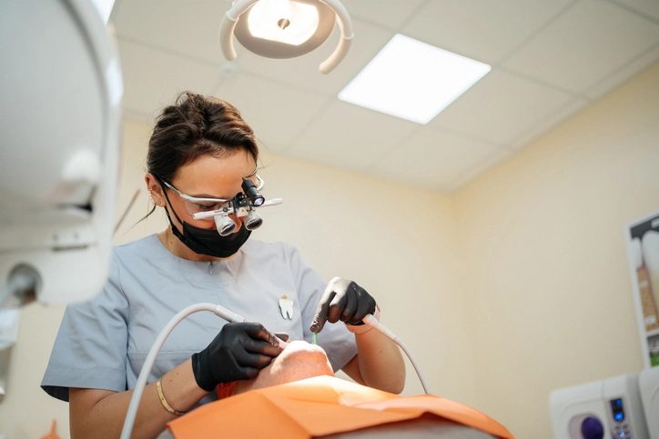 Dentista utilizando equipamentos de alta tecnologia e lupa cirúrgica para garantir um tratamento odontológico preciso e seguro ao paciente