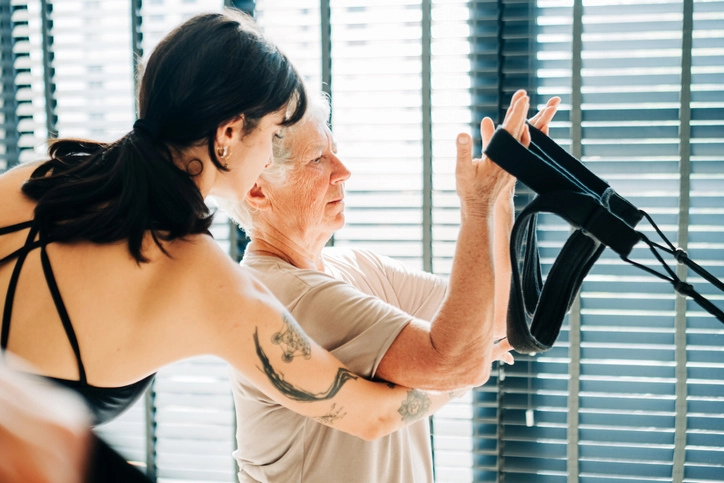 Fisioterapeuta acompanhando paciente idosa durante sessão de exercícios de fisioterapia e reabilitação física