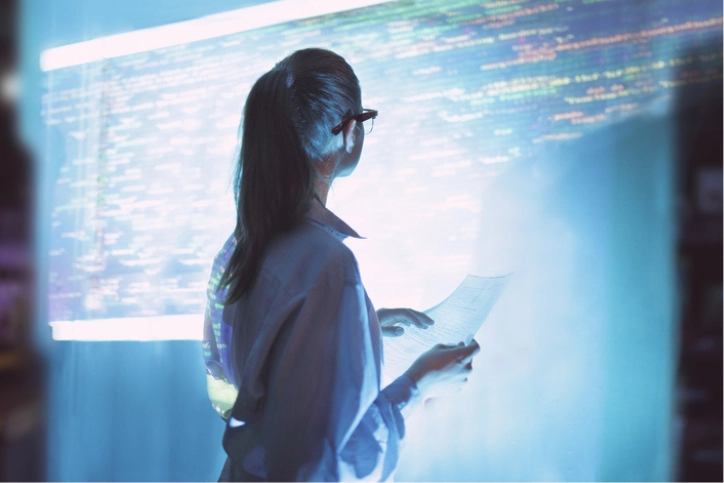 Mulher profissional de TI observando linhas de código em uma interface digital avançada para desenvolvimento de software
