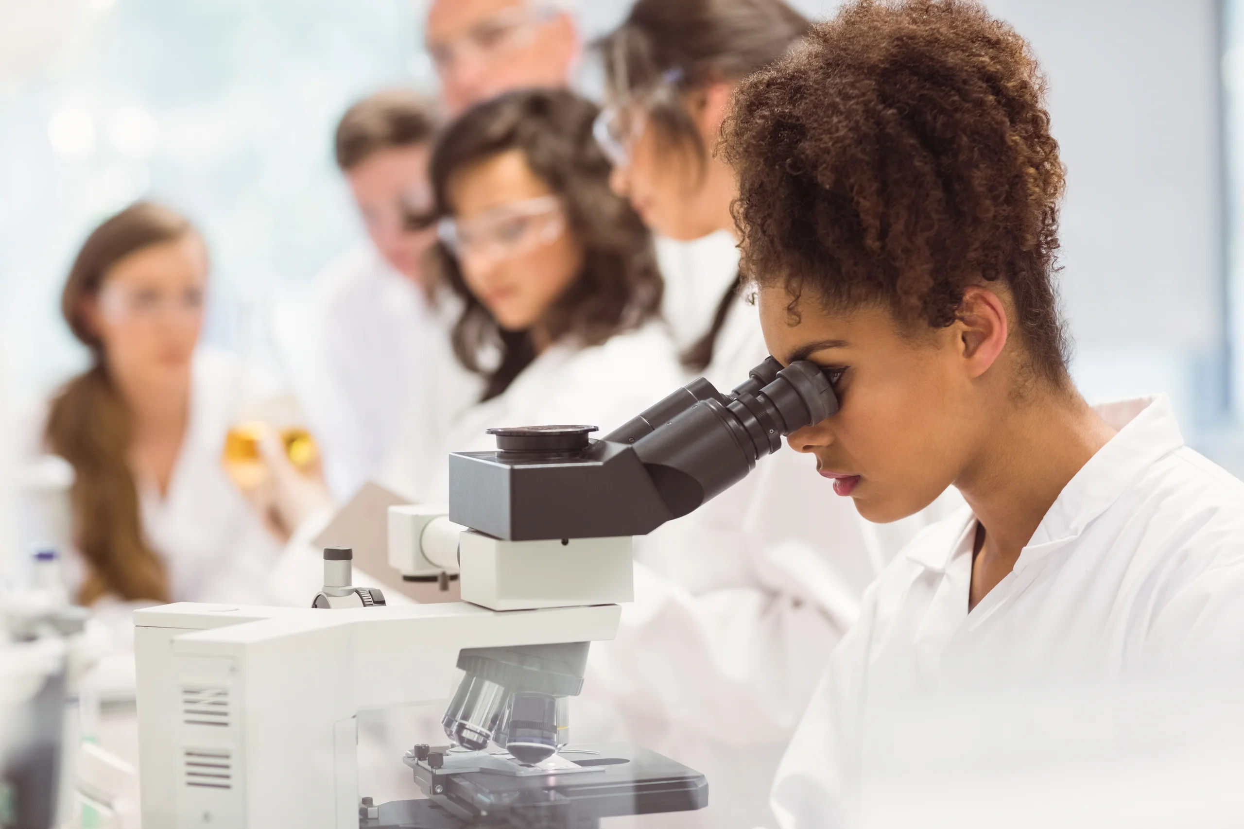 Estudante de biomedicina utilizando microscópio em laboratório acadêmico