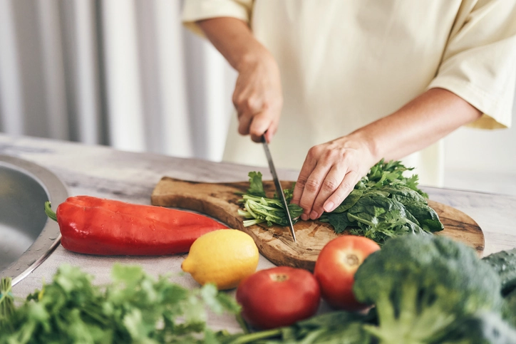 Pessoa preparando vegetais frescos e ervas em uma cozinha moderna para uma dieta saudável