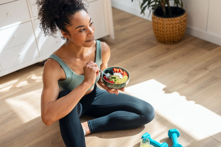 Mulher atleta mantendo uma alimentação equilibrada e saudável com frutas frescas após realizar exercícios físicos em casa