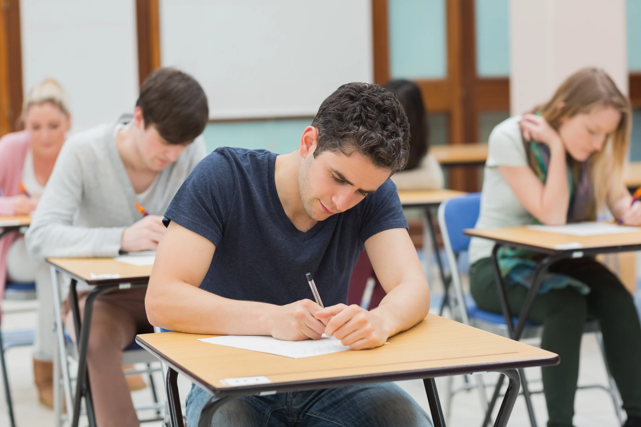 Alunos universitários focados escrevendo em uma avaliação acadêmica importante dentro de uma sala de aula