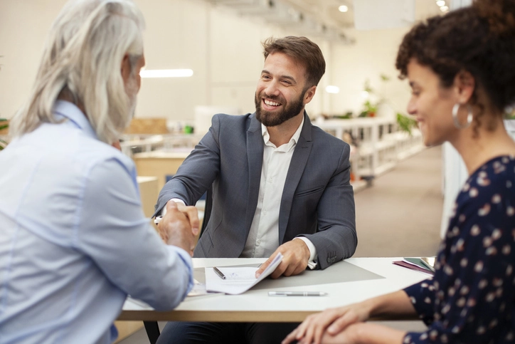 Homem de negócios sorridente cumprimentando cliente em reunião profissional no escritório