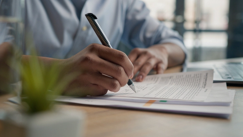 Pessoa assinando um documento formal em uma mesa de escritório