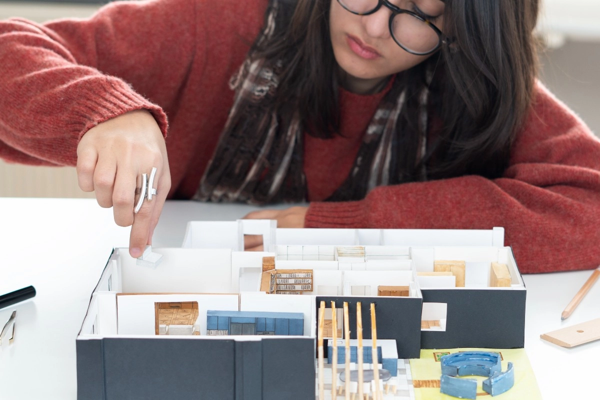 Estudante de arquitetura montando uma maquete detalhada de uma residência