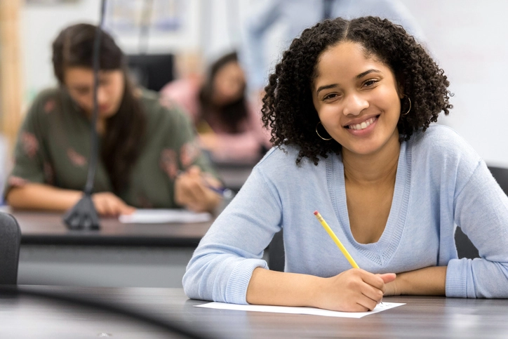 Estudante universitária sorrindo durante uma prova em sala de aula