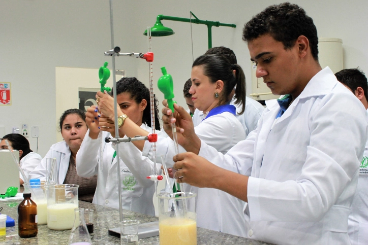 Estudantes em laboratório de química realizando experimentos com pipetas