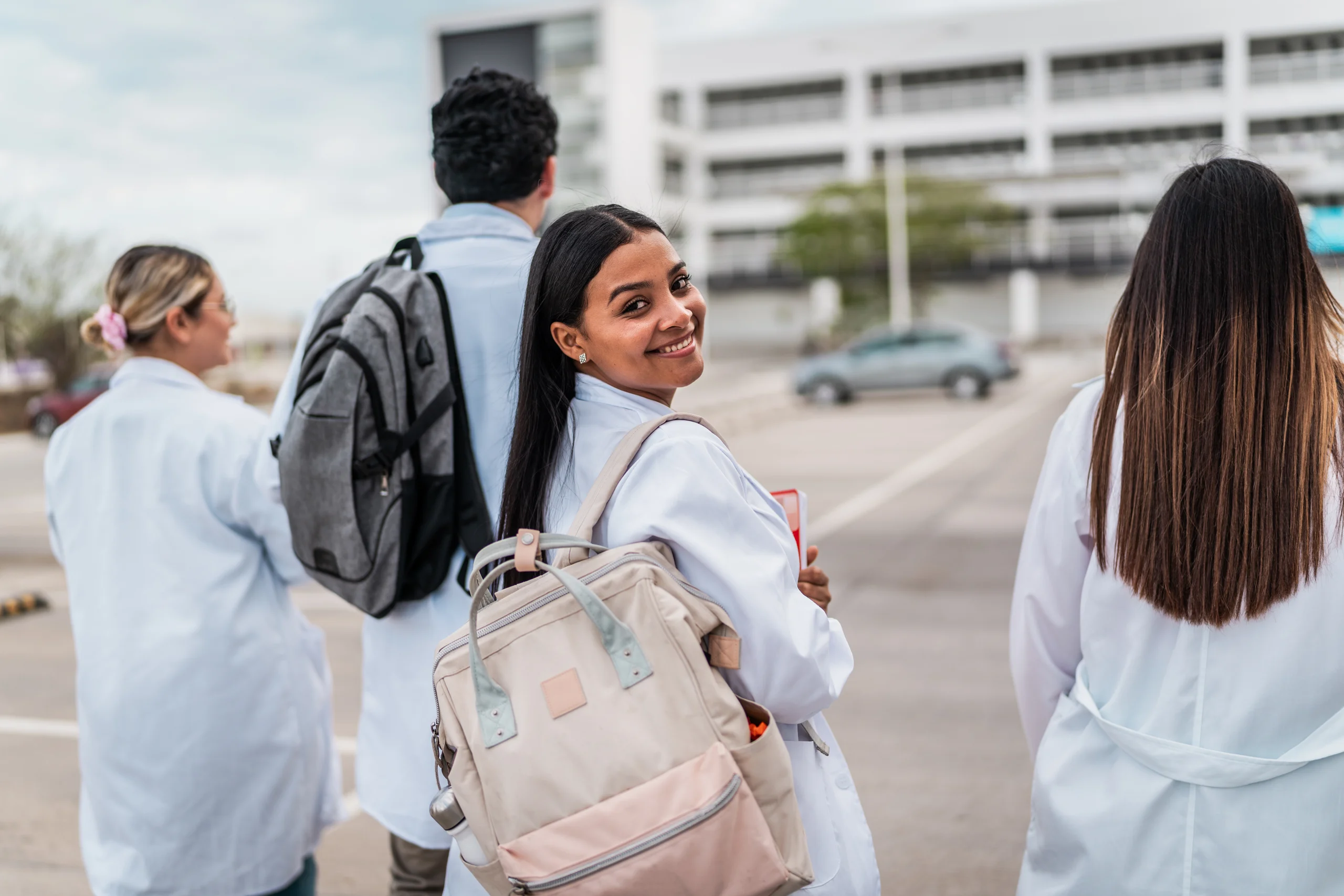 Estudantes de medicina vestindo jalecos brancos caminhando em campus universitário