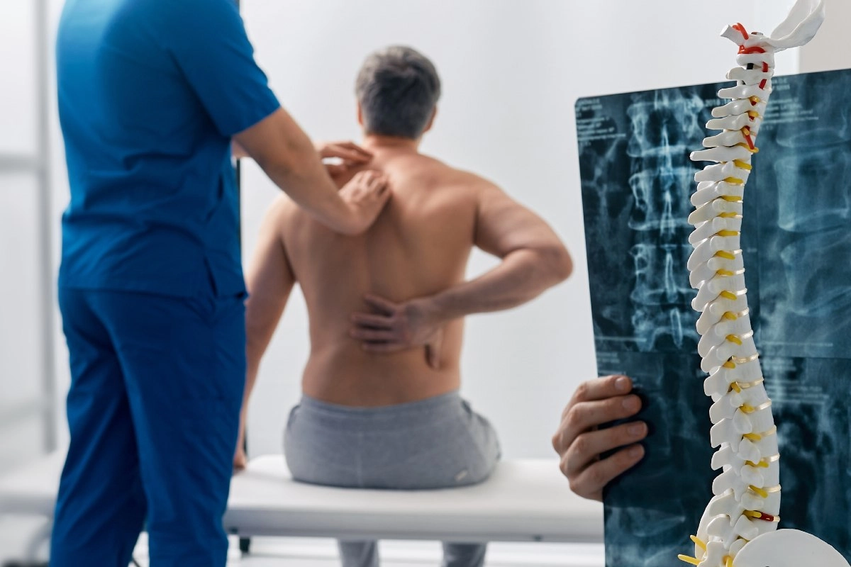 Médico do trabalho examinando a coluna de um paciente em consultório