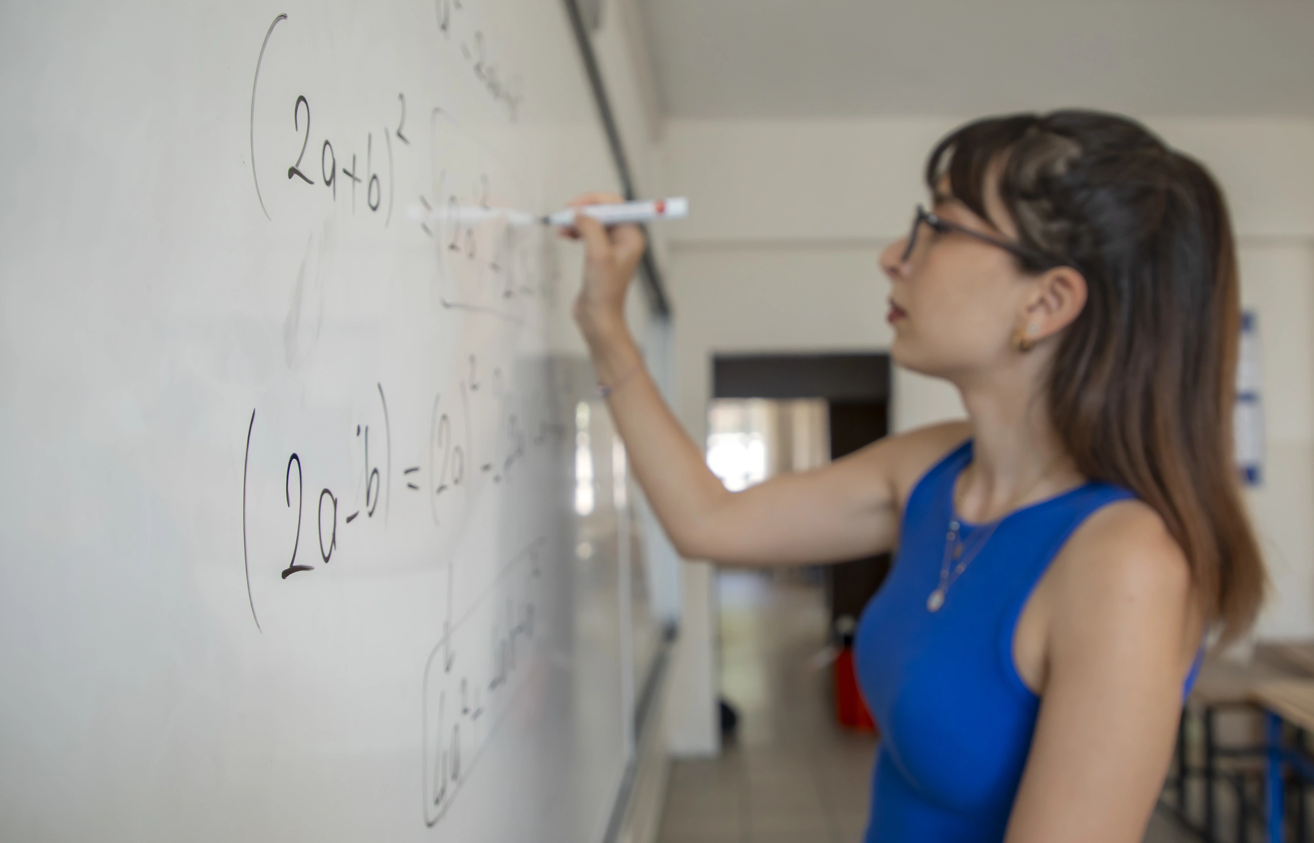 Professora escrevendo equações matemáticas em um quadro branco