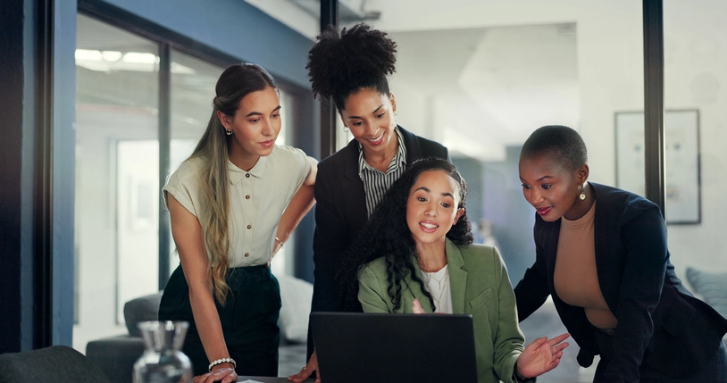 Mulheres profissionais colaborando em um projeto no escritório utilizando um notebook para análise de dados e planejamento estratégico