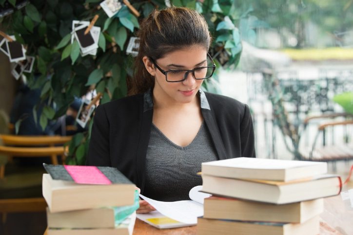Estudante focada lendo livros em um ambiente de biblioteca ou café