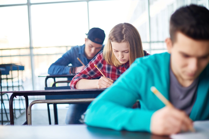 Estudantes concentrados realizando uma prova ou exercício em sala de aula