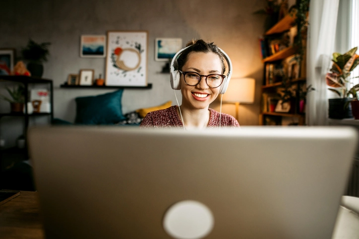 Mulher jovem sorridente participando de videochamada ou curso online em um ambiente de trabalho remoto confortável e organizado