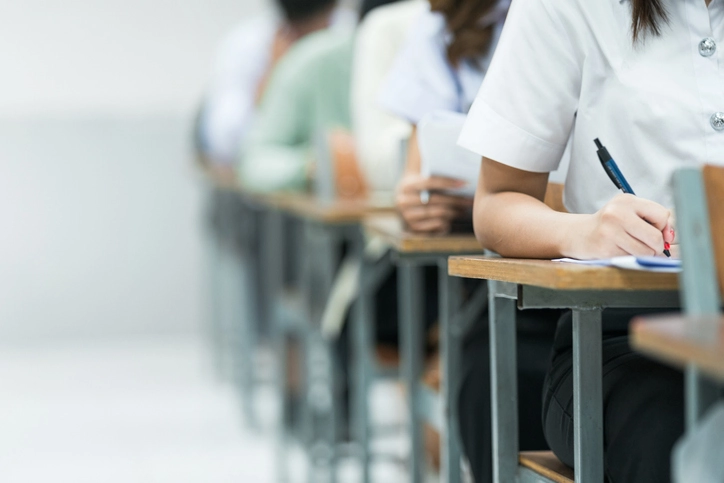 Alunos concentrados realizando uma prova escolar em sala de aula com foco em educação e avaliações acadêmicas.
