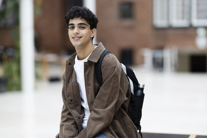 Estudante universitário sorrindo com mochila em campus escolar