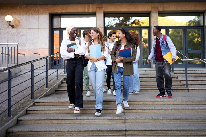 Grupo de estudantes universitários diversos conversando e descendo escadas no campus da universidade