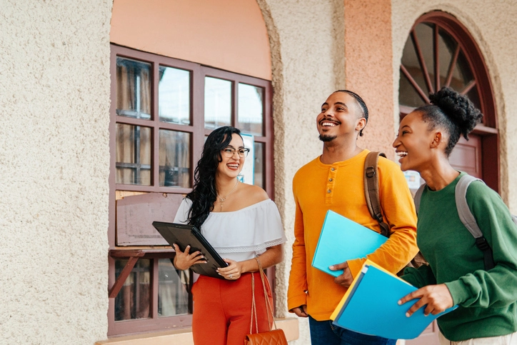 Grupo de estudantes diversos conversando alegremente no campus universitário