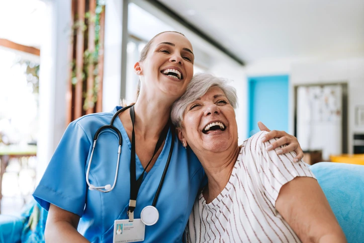 Cuidadora de saúde sorridente abraçando uma mulher idosa feliz