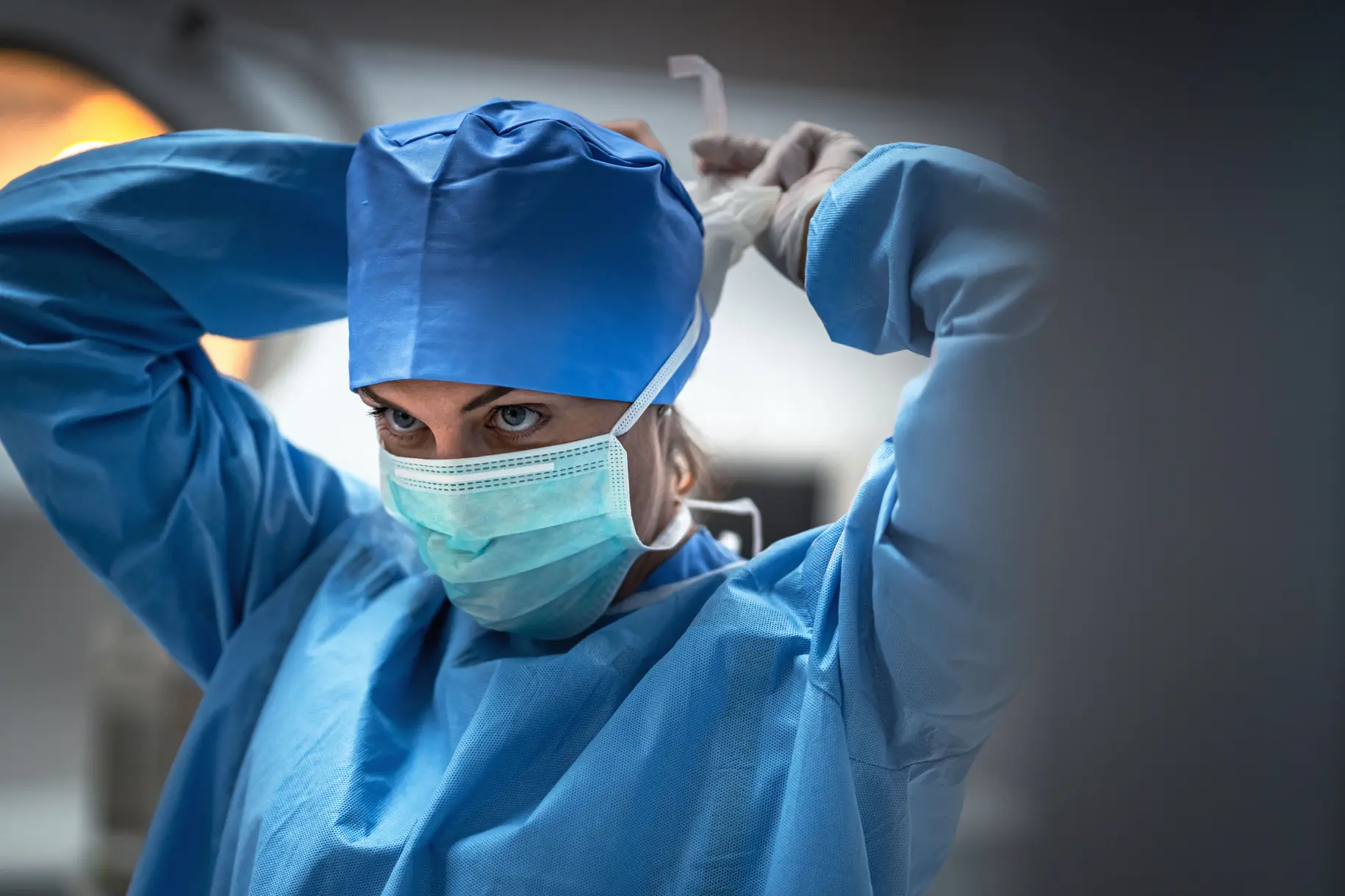 Profissional de enfermagem vestindo avental e máscara cirúrgica seguindo protocolos de biossegurança
