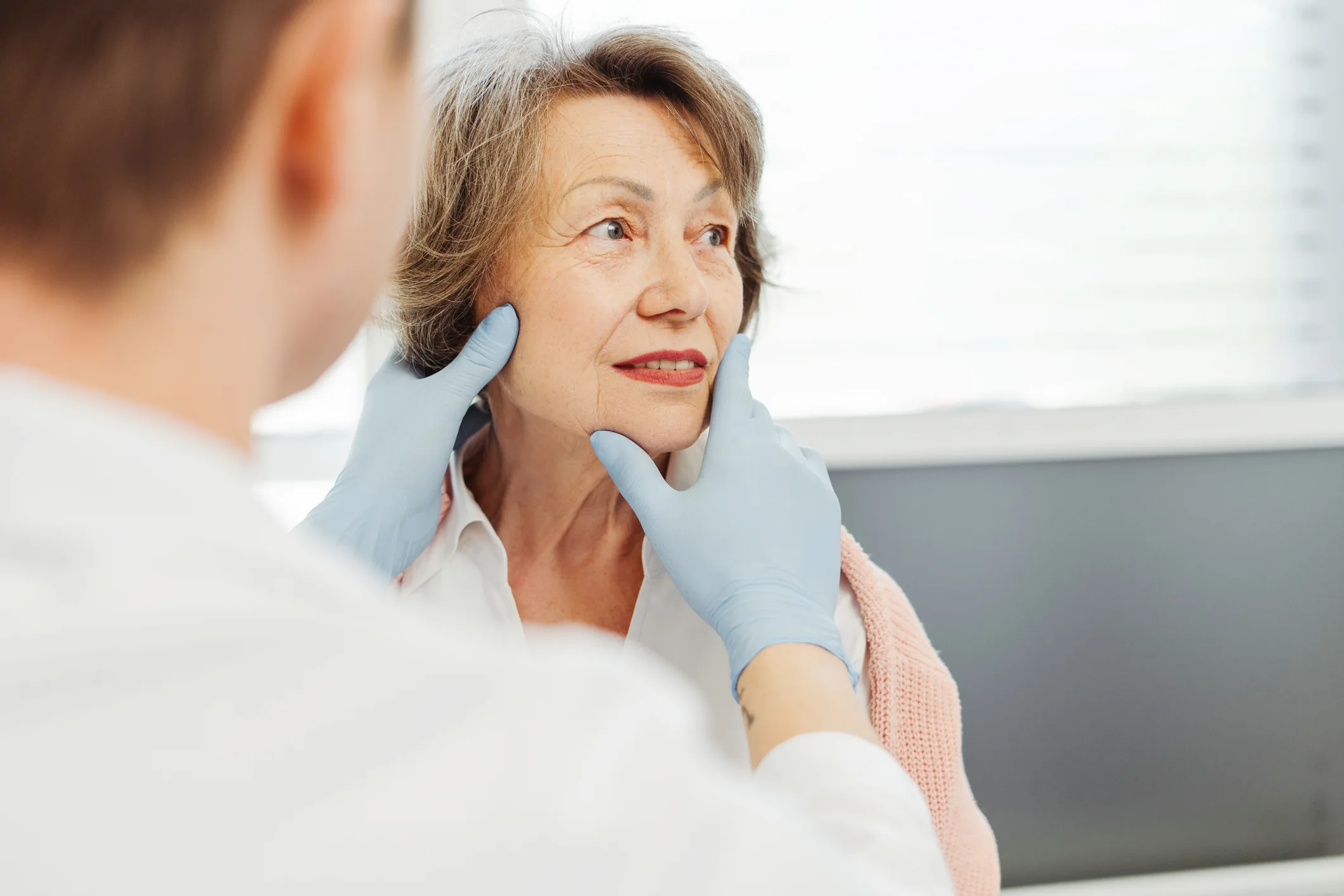 Biomédico realizando avaliação facial em paciente idosa para procedimentos estéticos