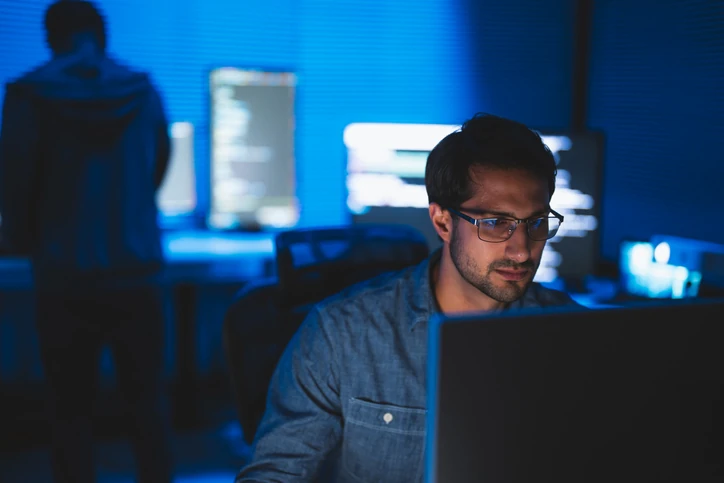 Desenvolvedor de software focado escrevendo código em ambiente de trabalho noturno com iluminação tecnológica