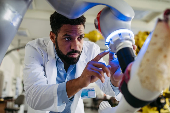 Pesquisador trabalhando com braço robótico em laboratório de tecnologia