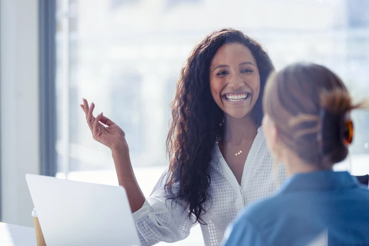Mulher sorridente conversando com colega em um ambiente de escritório moderno